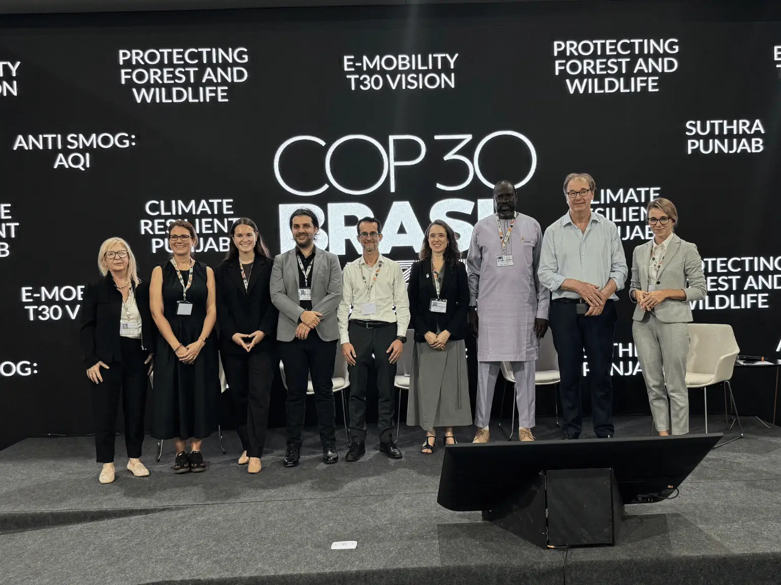 Nine people posing in front of COP30 Brasilia signage